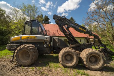 Polonya - Swietokrzyskie Voyvodeship 9 Mayıs 2023 saat 13: 53. Ponsse tarafındaki orman hasadı. Eski bir ormancının kulübesinin yanına park edilmiş on büyük tekerlek üzerinde. Ormandaki büyük ağaç kesme makinesi.. 