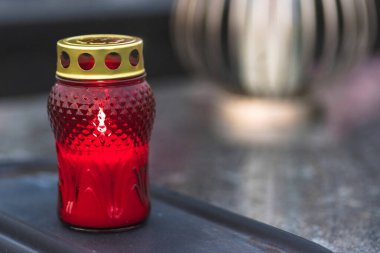  A burning red candle on a tombstone - All Saints Day.A burning candle intended to express memory of the deceased who have already achieved salvation.