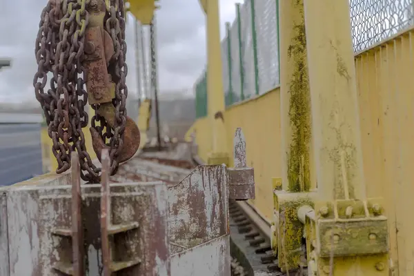 Metal chain on the road.Hooks, pulleys and rusty chains of a crane on a river dam.River dam with an electric water turbine - visible rusty crane utensils for changing the dam setting .