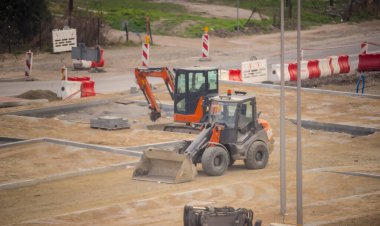  Polonya Ostrowiec Swietokrzyski 3 Mart 2024 saat 15: 49 'da. Hitachi yükleyici ve kazıcı bir otopark şantiyesinde. Küçük bir tekerlek yükleyici ve küçük kauçuk izli bir kazıcı - ikisi de Japonya 'da üretildi - bir şehir otoparkının döşenmesine yardım ediyor. .  