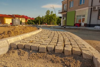 Yol inşaatı - büyük bir döner kavşak yapım aşamasında. Büyük bir döner kavşağın adası granit küplerden (ve aynı malzemeden yapılmış kaldırımlar) oluşur - kentte tarihi yapılar arasında bir yol inşa edilir..  