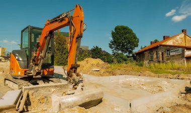 Yoldaki kazıcı. Polonya Ostrowiec Swietokrzyski 26 Mayıs 2024, saat 18: 05. Bir yol inşaatında Hitachi kazıcısı. Lastik raylarda küçük bir Japon kazıcısı mavi gökyüzünün altında bir inşaat alanında duruyor..  