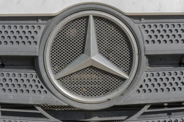 Mercedes - Benz amblemi beyaz bir kamyonun üzerinde - yakın plan. Polonya Ostrowiec Swietokrzyski 29 Nisan 2024 saat 15: 46 'da. Kamyon ızgarasında Mercedes işareti var. Izgarada arı ezilmiş büyük bir Mercedes kamyonu. İnşaat alanında bahar geldi..  