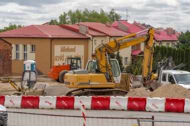 Yeni evle yeni bir yol inşaatı. Polonya Ostrowiec Swietokrzyski 22 Nisan 2024 saat 11: 29 'da. Liebherr kazıcısı bir yol inşaatında. Dönme dolap şantiyesindeki elektrik santralindeki büyük Alman sürüngen kazıcısı..  