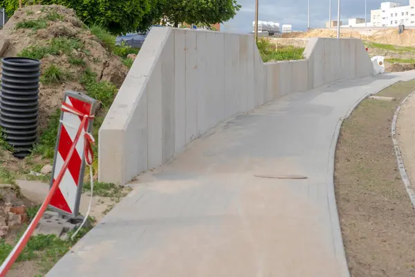 stock image New road construction site. Road construction site - sidewalk with retaining wall in the city. A newly built sidewalk, made of cobblestones, laid along a new road in the city. 