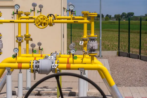 stock image Gas pipeline and equipment in a gas station. Natural gas pumping station among the spring fields. Yellow pipes, pressure gauges and valves - elements of the natural gas transmission installation . 