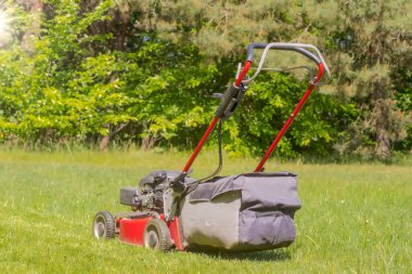 Çim biçme makinesi. Çimleri biçen bir benzin çim biçme makinesi. Büyük bir ev çimenliğinde çim biçen güçlü arka tekerleri olan bir petrol çim biçme makinesi..