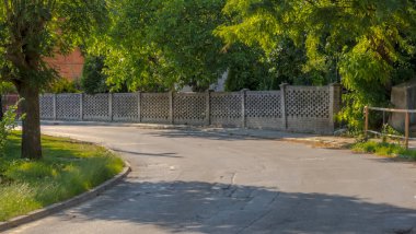 Parktaki eski tuğla ev. Bitkilerle dolu sessiz ve huzurlu bir sokak. Şehirde yaz mevsimi - ön planda bir tek aile evi bölgesi, açık tuğla bir duvar. . 