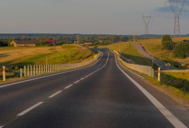 Kırsal kesimde asfalt yol. Bir yaz öğleden sonra güneş batarken banliyöde bir otoyol. Yaz öğleden sonra Ostrowiec yakınlarındaki bir tepede (çevre yolu)). 