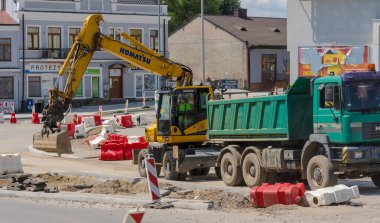 Yeni bir yol inşaatı. Yol tamiri. Polonya Ostrowiec Swietokrzyski 22 Temmuz 2024, saat 11: 14. Şehirdeki bir yol inşaatında Komatsu kazıcısı. Japon tekerli bir kazıcı yaz aylarında yol çalışması sırasında. 