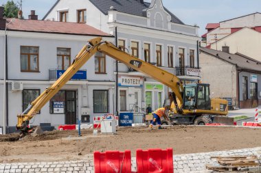 Polonya Ostrowiec Swietokrzyski 11 Temmuz, 2024: 12 Büyük Tırtıl kazıcısı - bir bahçe aracı olarak. Kavşağın ortasında, dönemecin ortasında Amerikan kazıcısını kullanarak bir bahçe yaratıyor. . 