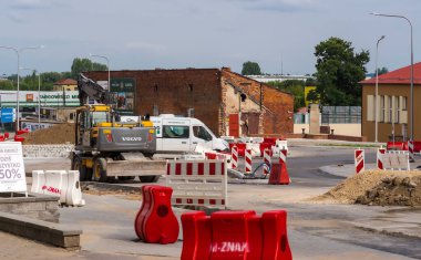 Polonya Ostrowiec Swietokrzyski 8 Temmuz 2024: 09. VOLVO kazıcı inşaatla meşgul. Eski bir tarihi tuğla binanın arka planına karşı İsveç kazıcısını kullanan bir kavşağın inşaatı .  