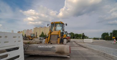 Bir yol inşaatı. CANGINI süpürücü bir kepçe yükleyici ve bir yol inşaatında VOLVO kepçe yükleyici monte edildi. Güzel, pitoresk bir gökyüzünün altında, bir yaz öğleden sonra bir yol inşaatı, şehrin yerleşim birimlerinin arasında.. 