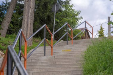 Parktaki metal merdiven. Tepedeki çelik korkuluklu kaldırım taşlarından yapılmış merdivenler yeşil ağaçların (ve diğer bitkilerin) arasında, şehrin büyüleyici bir köşesi. .