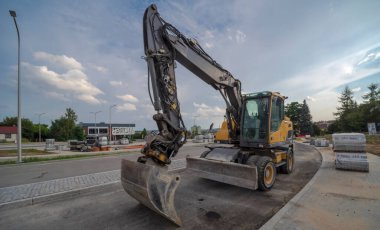 Polonya Ostrowiec Swietokrzyski 8 Temmuz, 2024: 01 PM. Volvo kazıcı bulutlu bir gökyüzünün altında şehrin yeni inşa edilmiş bir yolunda duruyor. İsveçli kazıcı, bir yaz akşamında, bulutlu bir gökyüzünün altında, taze bir yol yüzeyinde duruyor. . 