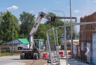 Poland Ostrowiec Swietokrzyski July 31, 2024 11:35 a.m. Demolition of an old building - CAT excavator in action. A white American excavator with a special hook at the end of the arm carries out demolition work - deconstructs an old brick building .  clipart