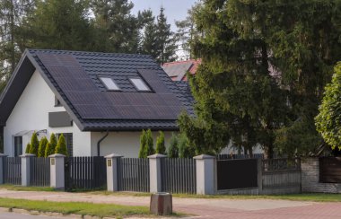 Bahçedeki modern ev. Şehirde ağaçların arasında küçük bir evin çatısındaki 