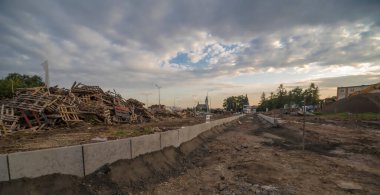 İnşaat. Şehirdeki bulutlu bir gökyüzünün (Ostrowiec Sw) altında yol inşaatı. Güzel, pitoresk ve muhteşem bulutlu yaz gökyüzü öğleden sonra şehirdeki inşaat alanının üzerinde..