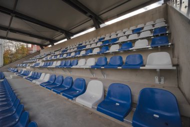 Spor stadyumunda bir stadyum. Okul spor stadyumundaki tribünler. Stadyumdaki seyirciler için tribünlerdeki plastik koltuklar.