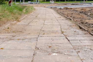 Road in the park. Arcy old destroyed sidewalk just before its demolition. Old concrete slab sidewalk just before its deconstruction - construction of a new road in the city . clipart