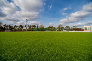 Yeşil çimenleri olan futbol stadyumu. Avrupa futbolu (futbol) mavi sonbahar gökyüzünün altında çimen sahası. Şehrin futbol sahasında (futbol) güneşli bir sonbahar günü (Ostrowiec). 