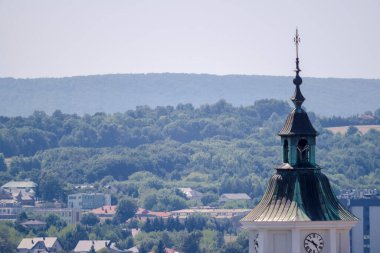  Ormanlık tepe ve dağların arkasında tarihi bir kilisenin kulesi. St. Michael Koleji Kilisesi - şehrin en eski kilisesi (Ostrowiec) yazın (hafif sisli) öğlen. 