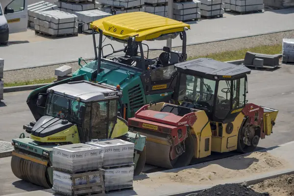 Polonya Ostrowiec Swietokrzyski 31 Temmuz 2024: 14. VOGELE asfalt makinesi ve AMMANN ve DYNAPAC yol silindirleri yolda. Şehirdeki neredeyse tamamlanmış bir yolun şantiyesinde inşaat makineleri var.. 