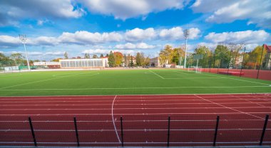 Spor okulu stadyum manzarası - futbol sahası (futbol sahası) ve koşu pisti - şehirdeki seyirci standlarından (Ostrowiec) - Polonya Altın Sonbahar 'da güzel bir çevrede yüksek direklerde projektörleri olan.  