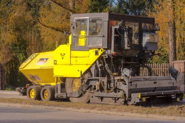 İnşaat alanındaki makine. Polonya Ostrowiec Swietokrzyski 16 Kasım 2024: 27 Bir sonbahar günü TITAN asfalt makinesi. Büyük bir asfaltlama makinesi yenilenmiş bir yolun kenarında sonbahar 