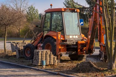Polonya Ostrowiec Swietokrzyski, 16 Kasım 2024, saat 13.33, FIAT KOBELCO - inşaat alanında kepçe yükleyici. Şehirdeki kaldırım ve bisiklet yolunun yeniden inşası - şehir yolunun kenarında sonbahar öğleden sonra. 