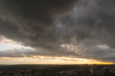 Şehrin üzerinde dramatik bir gün batımı. Gökyüzünde gün batımı şehrin üzerinde destansı bulutlarla kaplıdır (Ostrowiec Swietokrzyski). Kasvetli, karanlık bulutların şehri gölgelediği dramatik bir gökyüzü hakim.. 