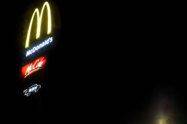 Polonya Ostrowiec Swietokrzyski 18 Ocak 2025, McDonald 's tabelası gecenin karanlığında pırıl pırıl parlıyor. McDonald 's simgesi karanlık bir gece gökyüzüne karşı aydınlandı. İkonik sarı 