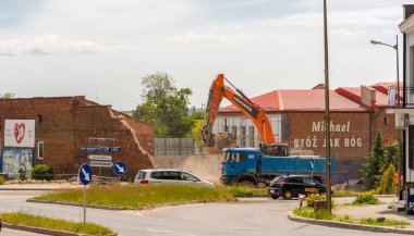 Şehirde yeni bir yol inşa ediliyor.Polonya Ostrowiec Swietokrzyski 6 Haziran 2023 saat 10: 49 'da tarihi papaz evinin yıkımı. Çöp kamyonu. Mavi bir damperli kamyon şirketten turuncu bir kazıcı olarak yerleştirildi..