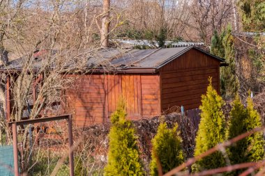 İlkbaharı bekledikleri için, o cennetlerdeki bahçeler. Güneşli bir ocak gününde ahşap tahıl tahsis evi. Bir bahçenin ortasında eğimli çatılı küçük bir ahşap bölme evi bulunuyor. Yapının doğal bir ahşap kaplaması var ve etrafı yapraksız ağaçlarla çevrili. .