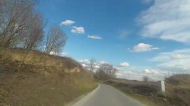 Ostrowiec Swietokrzyski yakınlarındaki tepelerden geçerek, yay ve mavi gökyüzü üzerinden uçuyor. Asfalt kıvrımlı yol, Ostrowiec Swietokrzyski civarındaki güzel tepelere doğru esiyor.. 