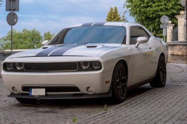 Polonya Ostrowiec Swietokrzyski 19 Mayıs 2025: 32. DODGE CHALLENGER bir bahar öğleden sonra, kaldırım taşı caddesinde park, siyah yarış şeritleri kapak. Arabanın pürüzsüz, kaslı tasarımı renkli camlar ve siyah alaşımla tamamlanıyor..