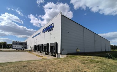 Polonya Ostrowiec Swietokrzyski 17 Ağustos 2025: 53. SIGNAL mobilya - lojistik merkezi açık, mavi bir gökyüzü altında mavi bir yaz gökyüzü altında. Yapı, yan tarafında birden fazla yükleme bölmeleri olan açık gri panellerden yapılmıştır. Asfaltlı bir alan. 