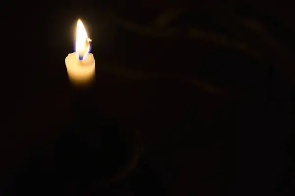 Single Candle with flame in the dark place, isolated black background