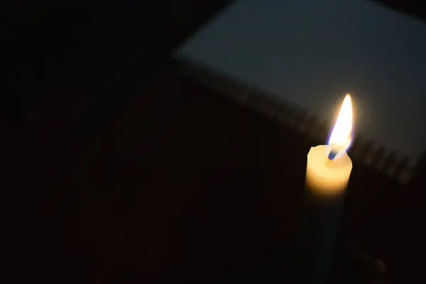 Single Candle with flame in the dark place with book blur background