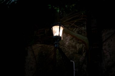 Ürkütücü karanlık bir gecede eski duvarda asılı klasik bir sokak feneri. Kopya alanı olan siyah sokak lambası