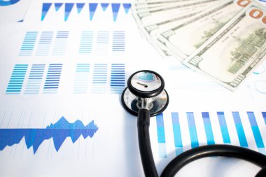 Stetoskop, Amerikan doları banknotu ve basılı istatistik tablosu. Mali, hesap, istatistik ve mali sağlık kavramı