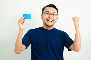 Mutlu Asyalı adam kredi kartıyla kutlama pozu veriyor. Bankacılık, finansal konsept ve el kaldırma hareketi. Mavi renk konsepti