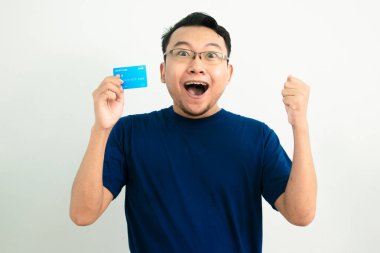 Mutlu Asyalı adam kredi kartıyla kutlama pozu veriyor. Bankacılık, finansal konsept ve el kaldırma hareketi. Mavi renk consepsi