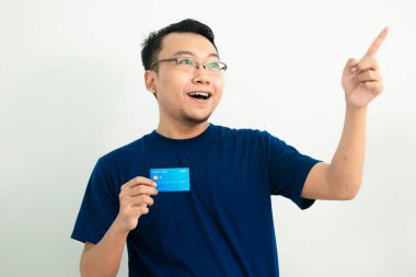 Mutlu Asyalı adam kredi kartını işaret ederek tutuyor. Bankacılık, finansal izole, mavi renk konsepti