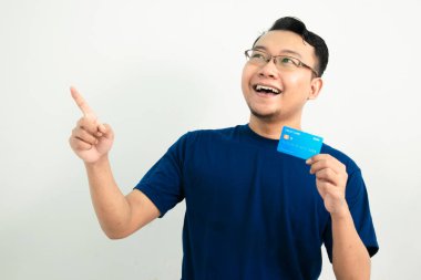 Mutlu Asyalı adam kredi kartını işaret ederek tutuyor. Bankacılık, finansal izole, mavi renk konsepti
