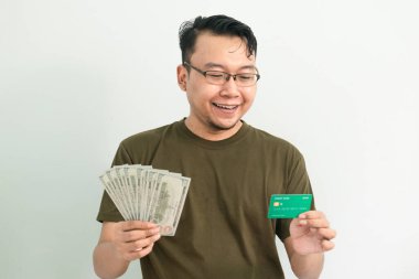 Mutlu Asyalı adamın kredi kartı ve parası var. Bankacılık, finansal izole, yeşil renk konsepti