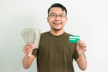 Mutlu Asyalı adamın kredi kartı ve parası var. Bankacılık, finansal izole, yeşil renk konsepti