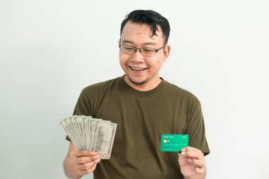 Mutlu Asyalı adamın kredi kartı ve parası var. Bankacılık, finansal izole, yeşil renk konsepti