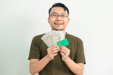 Mutlu Asyalı adamın kredi kartı ve parası var. Bankacılık, finansal izole, yeşil renk konsepti