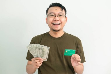 Mutlu Asyalı adamın kredi kartı ve parası var. Bankacılık, finansal izole, yeşil renk konsepti